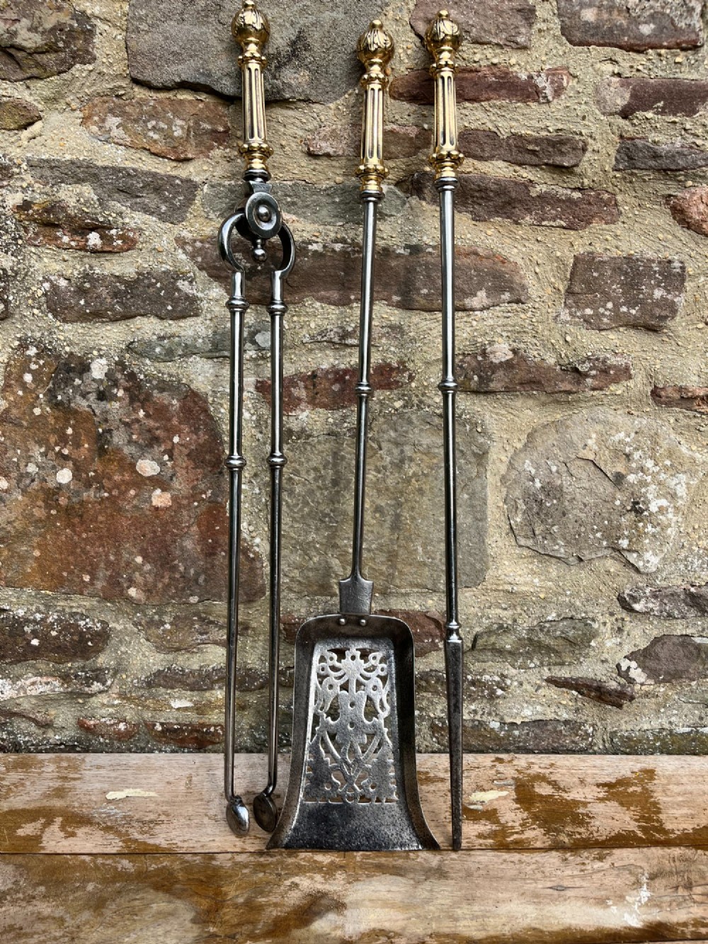 A three-piece set of antique fire tools including a shovel, poker, and tongs with brass handles and steel shafts. View III