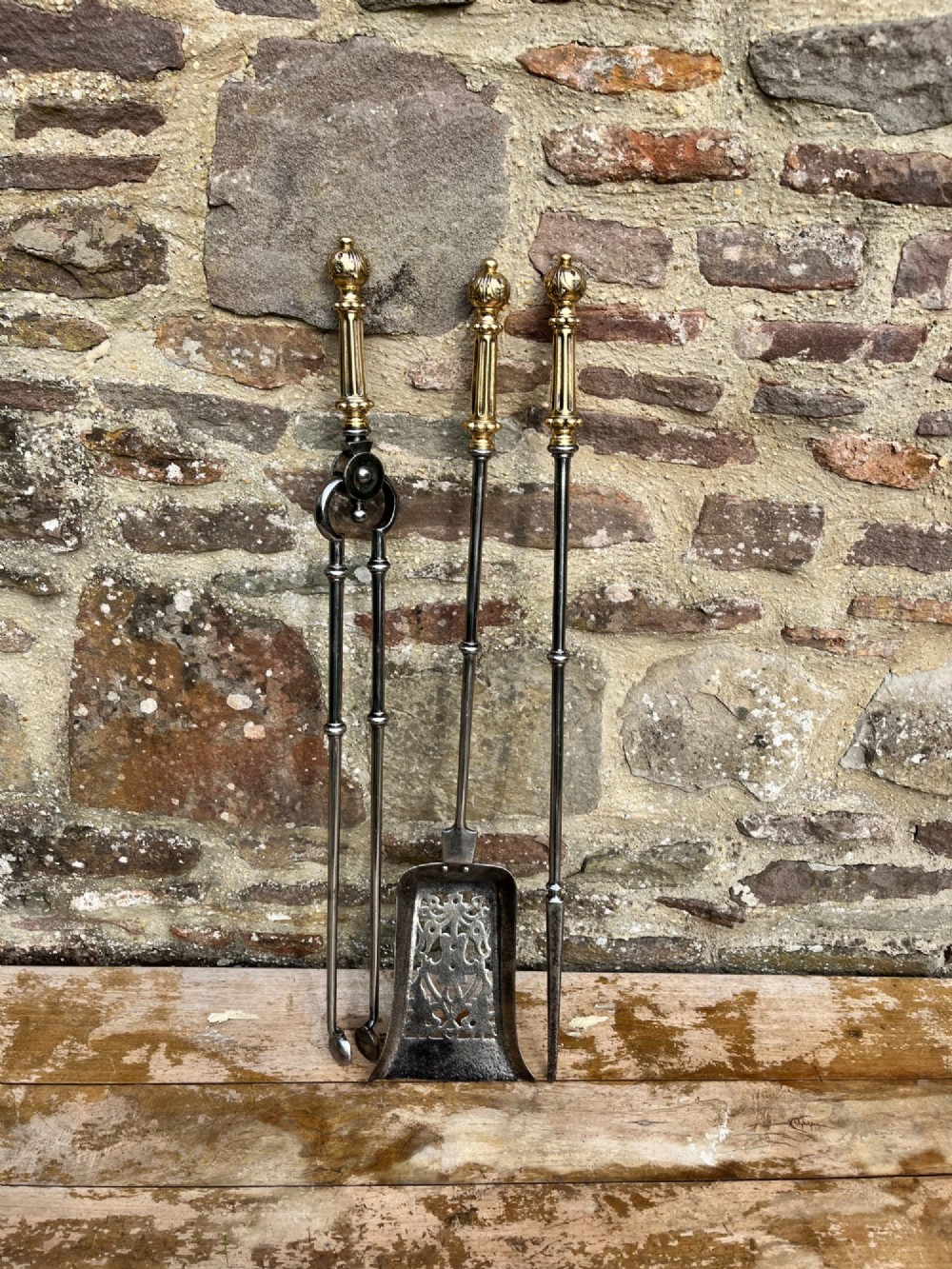 A three-piece set of antique fire tools including a shovel, poker, and tongs with brass handles and steel shafts. View IV