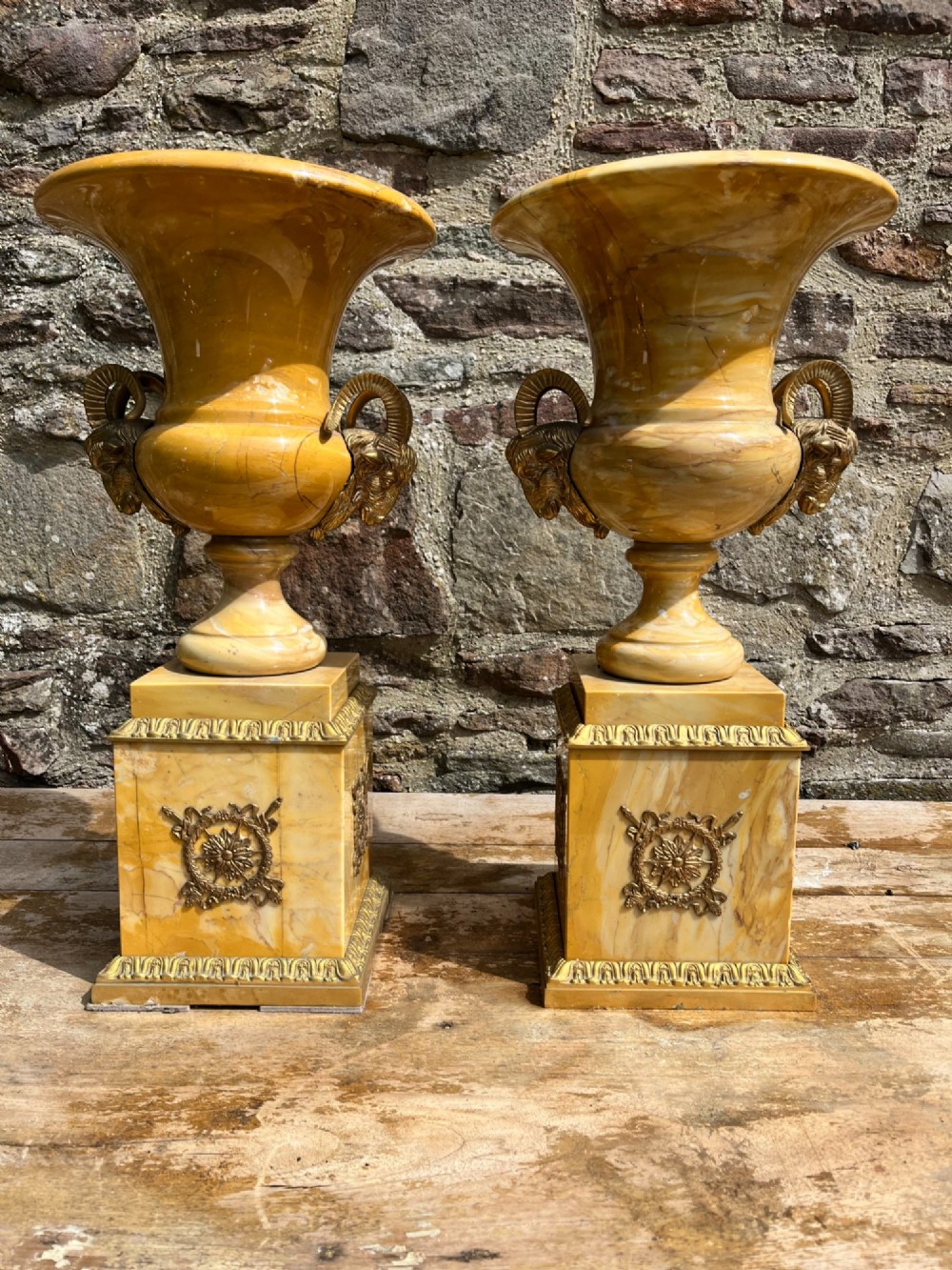 Pair of yellow veined Sienna marble campana urns featuring brass ram head handles and square plinths decorated with floral appliques. View III
