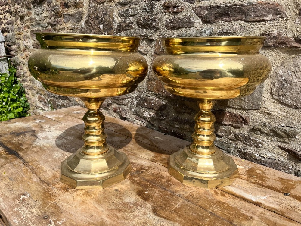 A pair of polished brass goblets featuring wide rounded bowls, turned baluster stems, and octagonal bases. View V