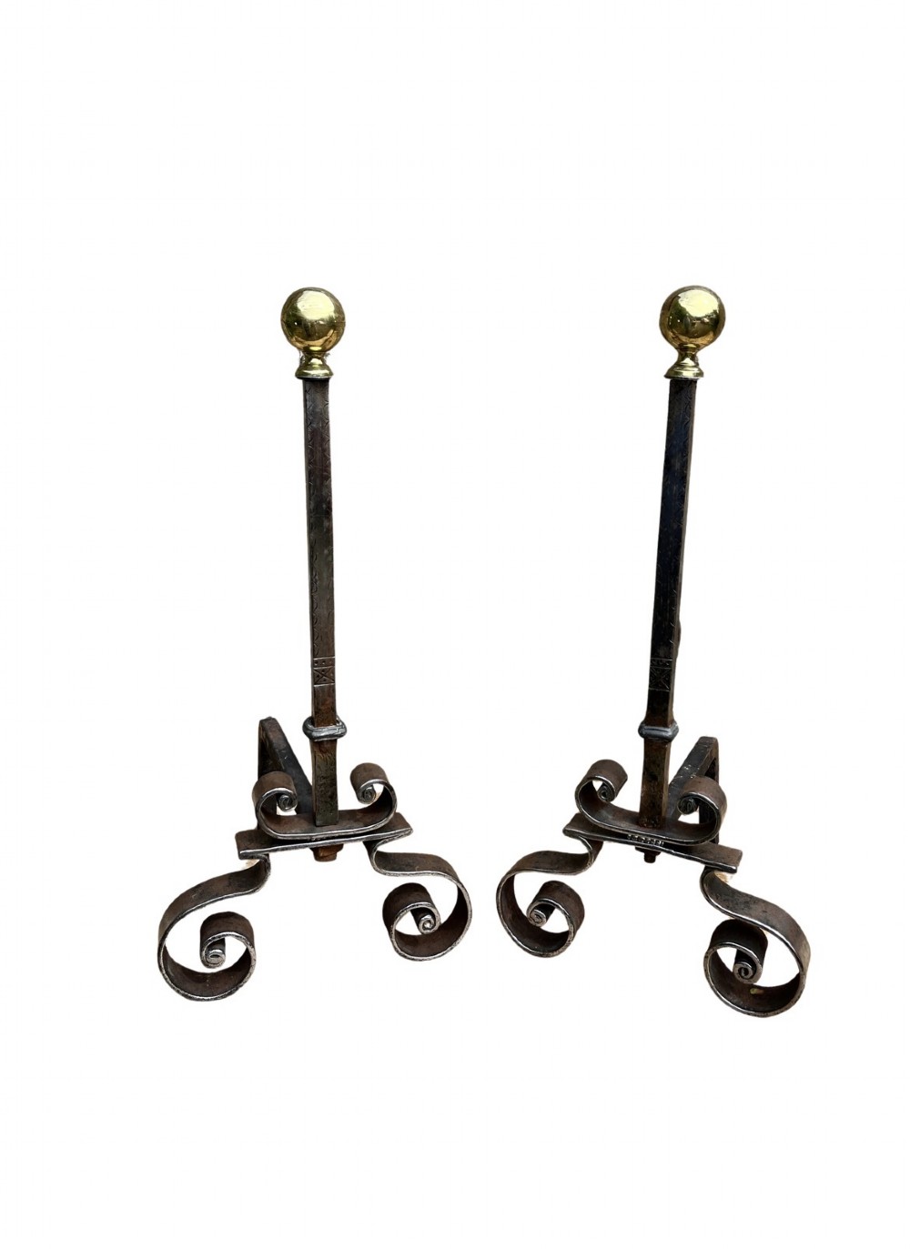 A pair of French wrought iron fire dogs featuring scroll legs and spherical brass finials atop vertical stems.