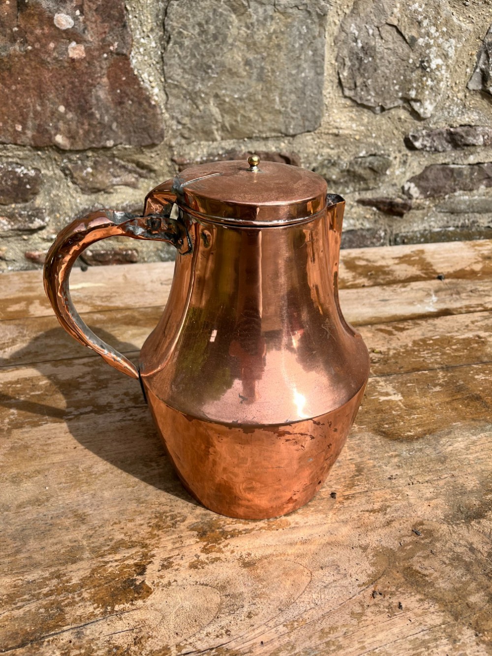 A polished antique copper milk jug featuring a hinged lid, small top finial, and a broad curved handle. View III