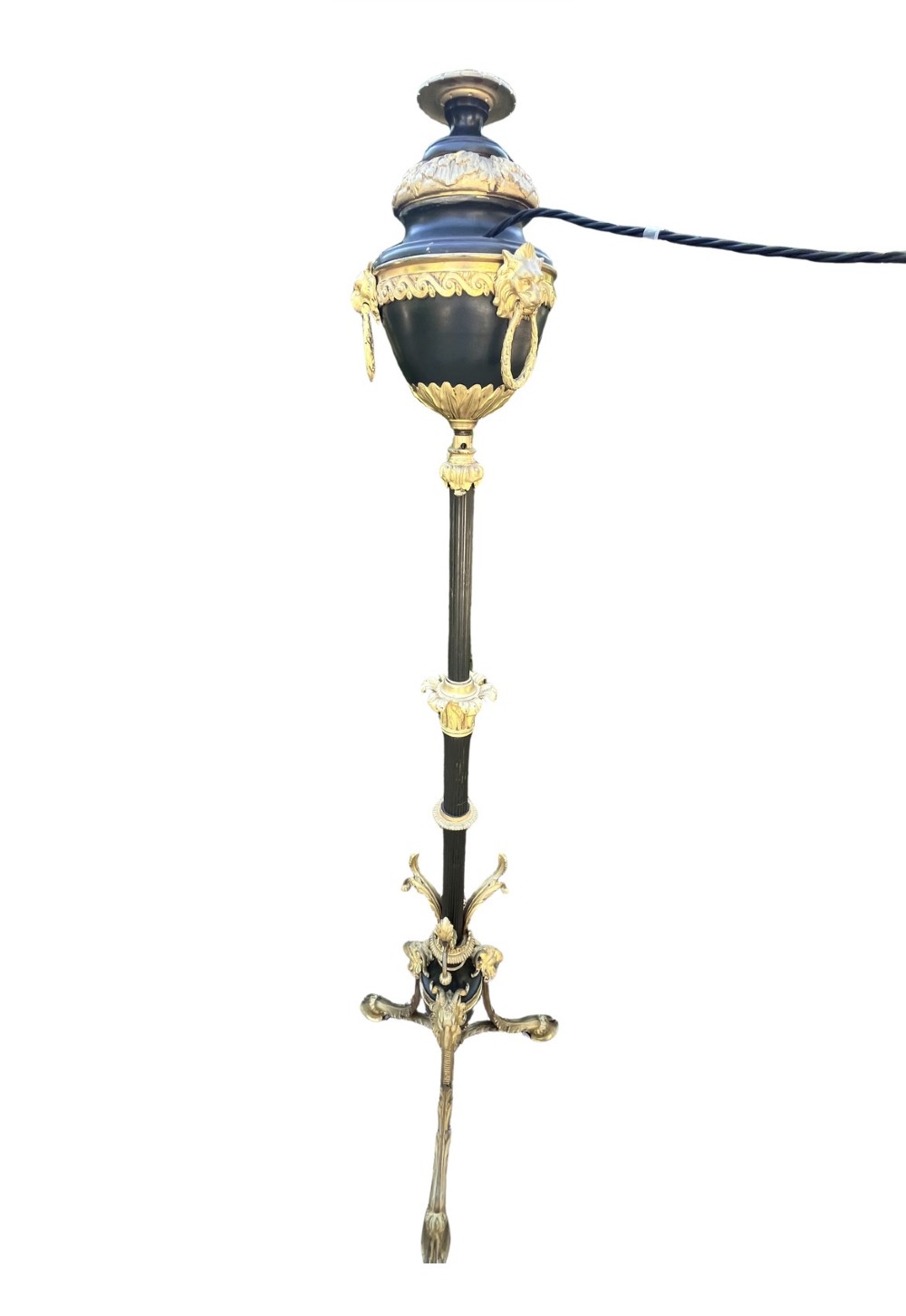 A Victorian gilt bronze and black patinated metal standard floor lamp with a lion mask urn top section, fluted shaft, and tripod paw feet.