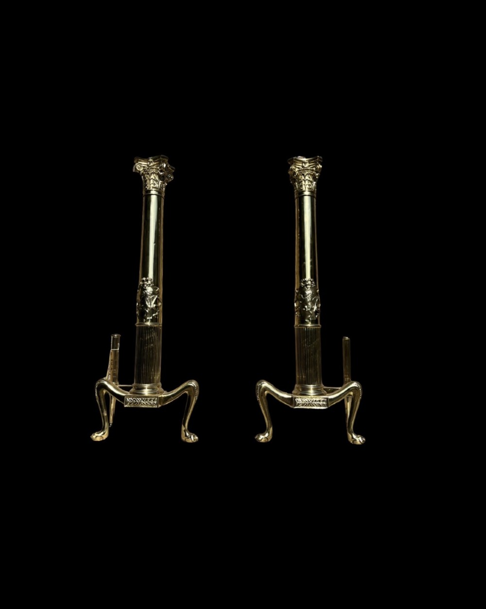 A pair of tall polished brass fire dogs featuring fluted Corinthian columns with relief crests and cabriole legs ending in claw feet. View II