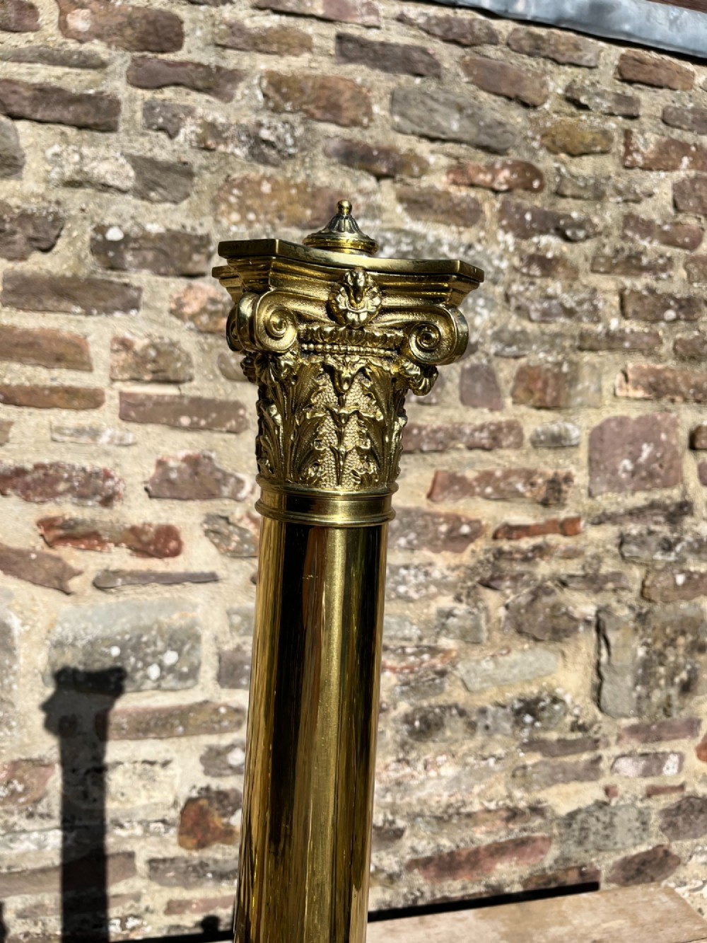 A pair of tall polished brass fire dogs featuring fluted Corinthian columns with relief crests and cabriole legs ending in claw feet. View III