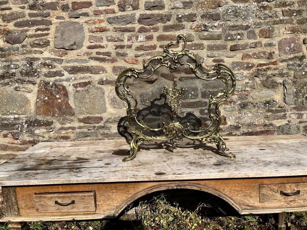 An ornate French Rococo style gilt bronze fire screen featuring elaborate scrolled rocaille framework, cabriole legs, and a central decorative motif. View V