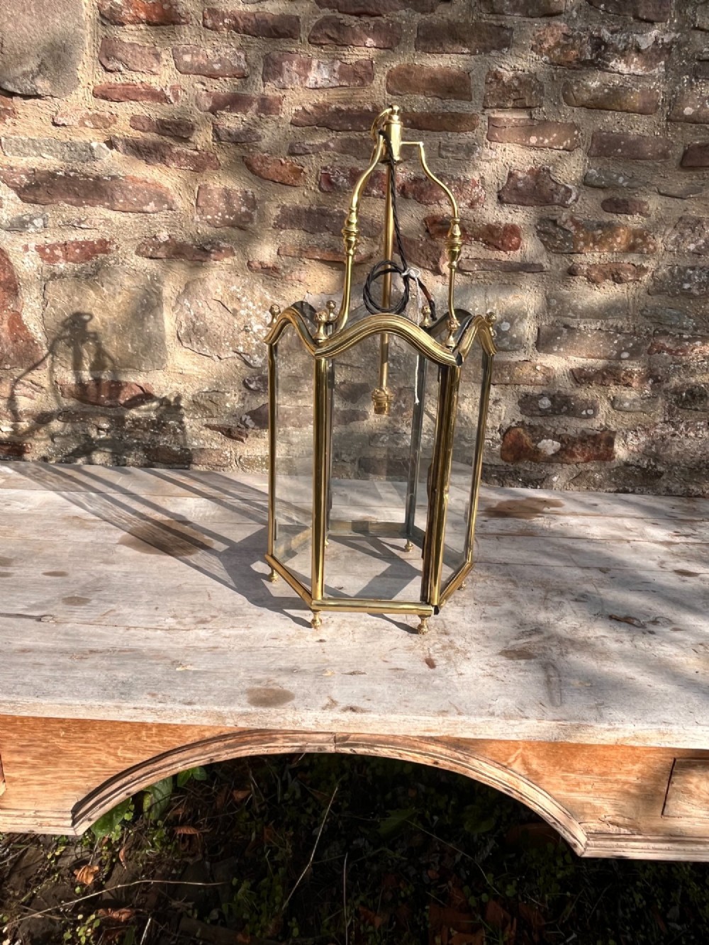 A Victorian brass hall lantern featuring a shaped frame, clear glass side panels, decorative finials, and an upper suspension loop. View III
