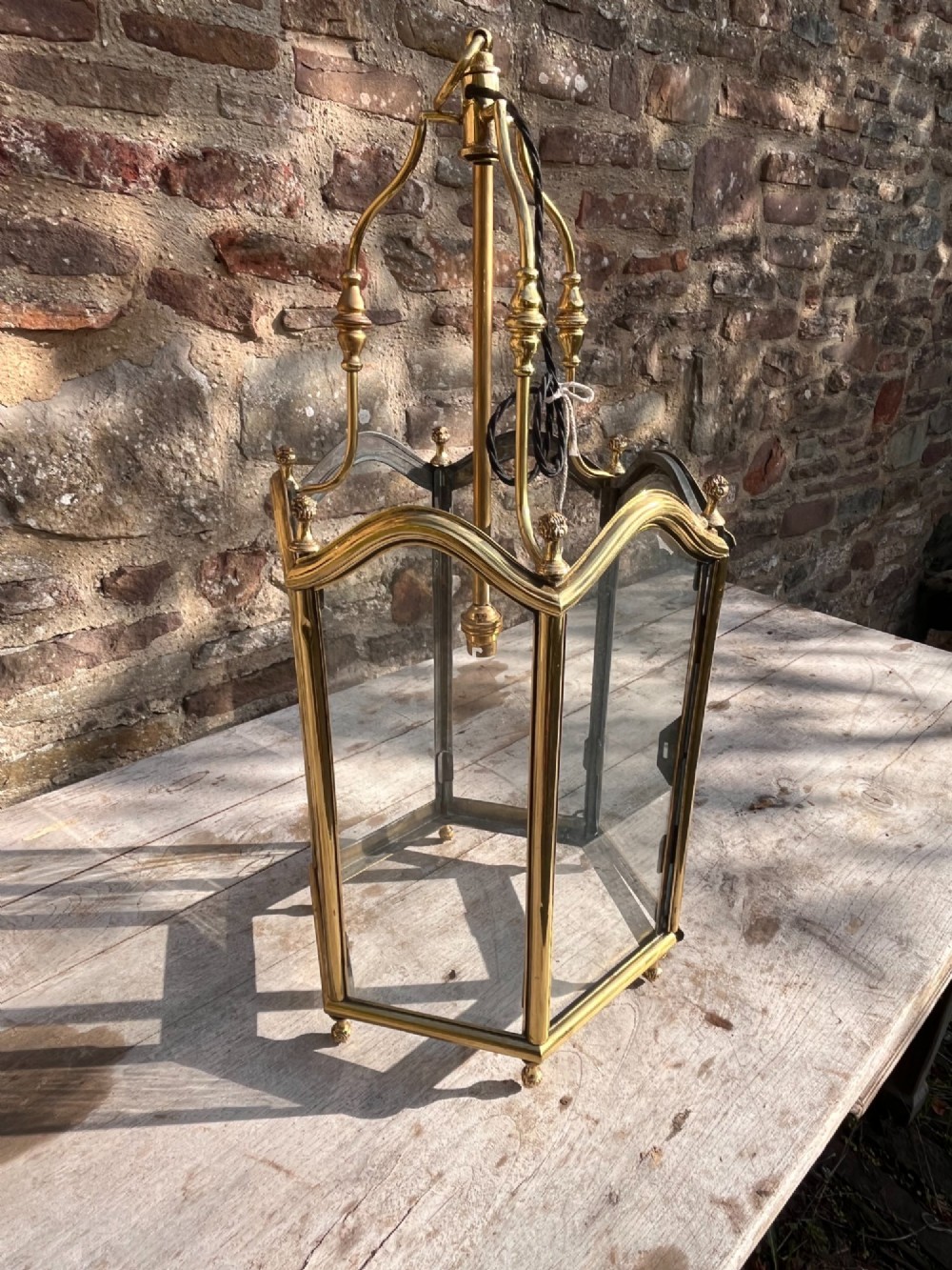 A Victorian brass hall lantern featuring a shaped frame, clear glass side panels, decorative finials, and an upper suspension loop. View IV