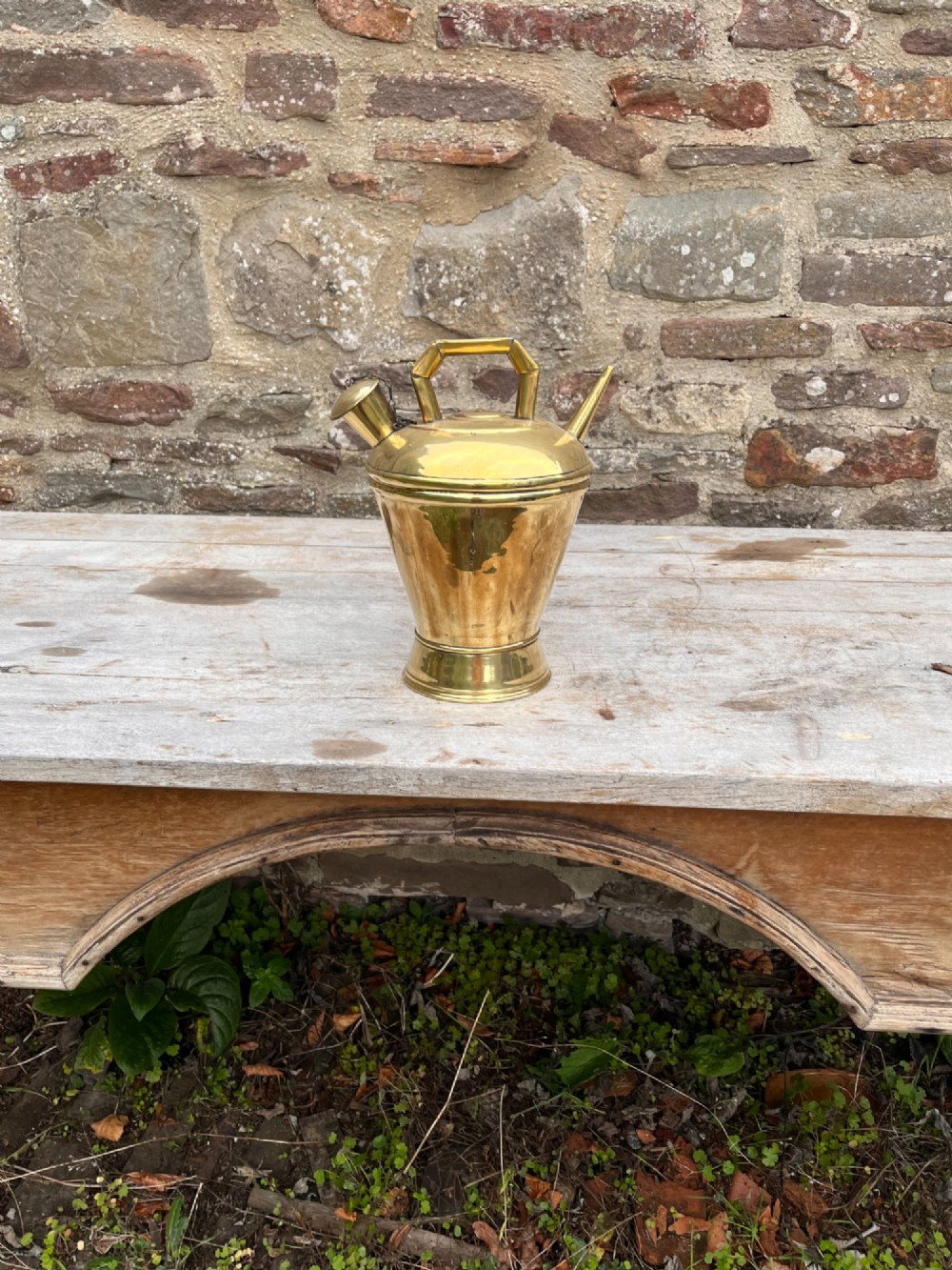 An antique polished brass oil vessel featuring an angular top handle, a long thin pouring spout, and a capped filler spout on a pedestal base. View III