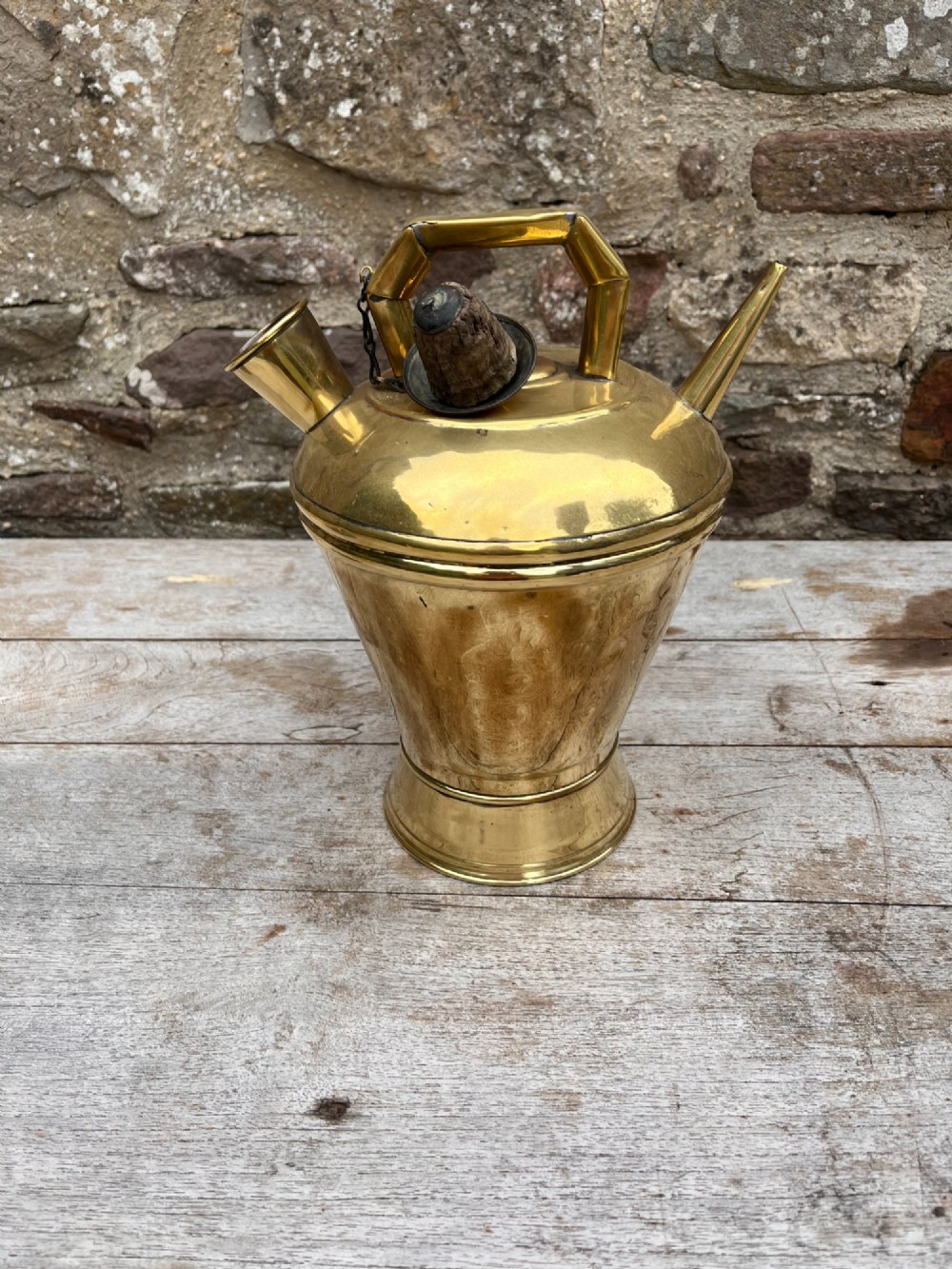 An antique polished brass oil vessel featuring an angular top handle, a long thin pouring spout, and a capped filler spout on a pedestal base. View IV