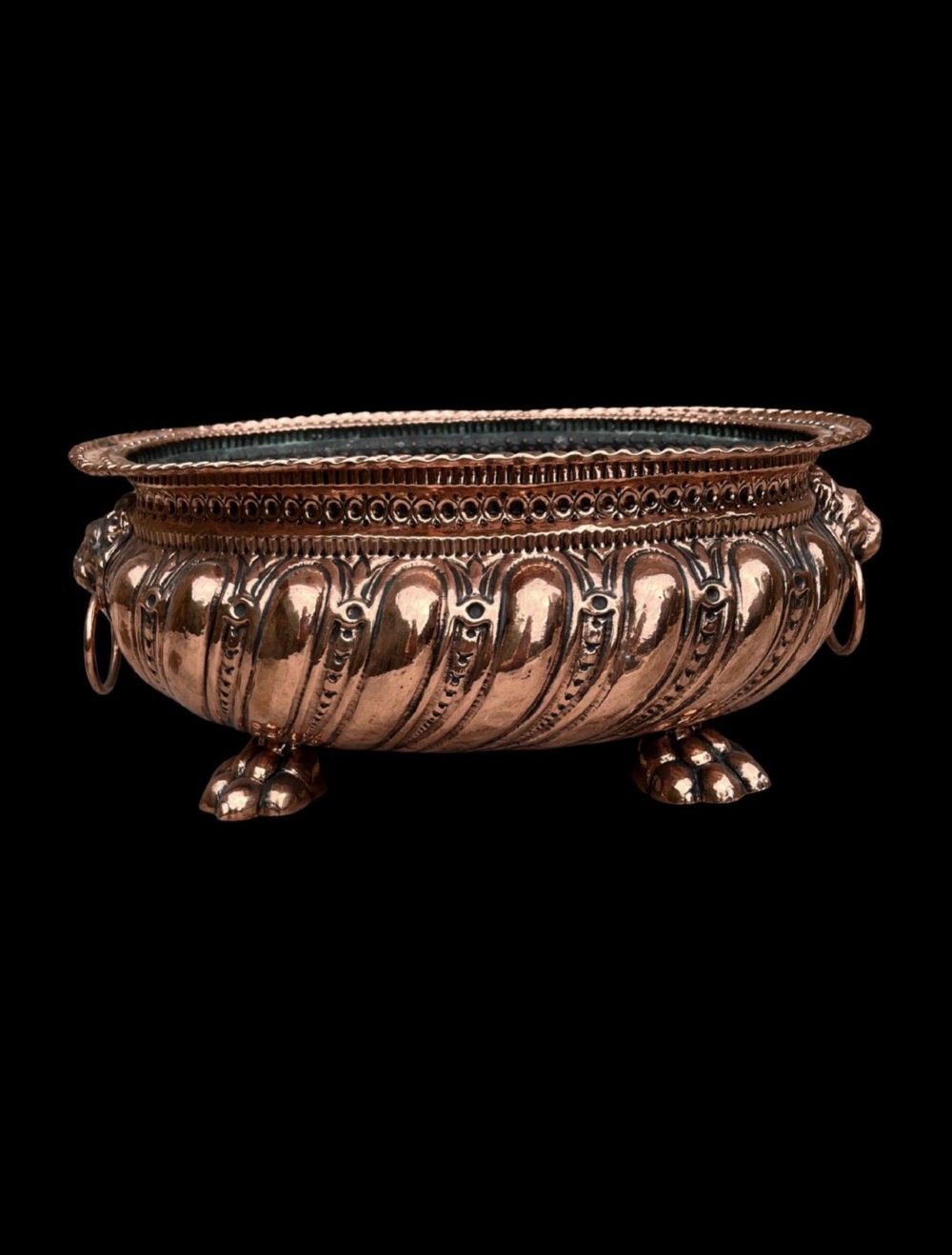An oval antique copper jardiniere featuring gadrooned body panels, lion mask drop-ring handles, and cast paw feet. View II