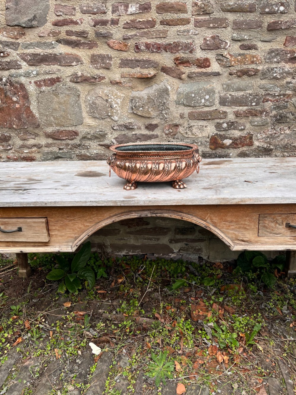 An oval antique copper jardiniere featuring gadrooned body panels, lion mask drop-ring handles, and cast paw feet. View VI