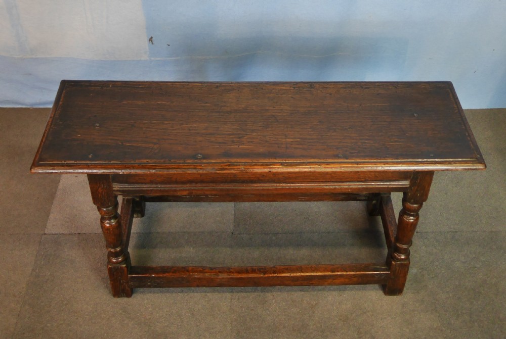 A low rectangular dark oak coffee table featuring baluster-turned legs, block feet, and a surrounding low box stretcher. View V