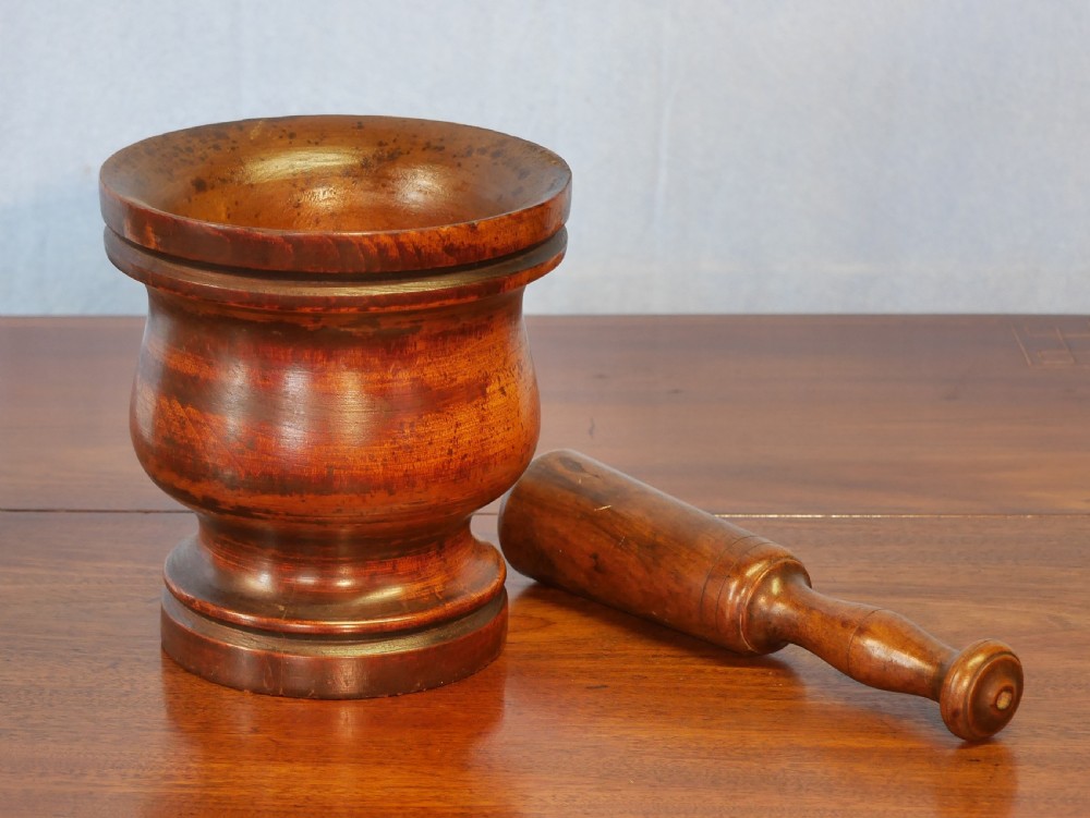 A turned walnut treen mortar with a moulded rim and base, accompanied by a matching turned wooden pestle. View II