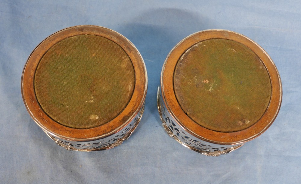 A pair of circular silver-plated wine coasters featuring pierced scrollwork sides and turned wooden bases. View VIII