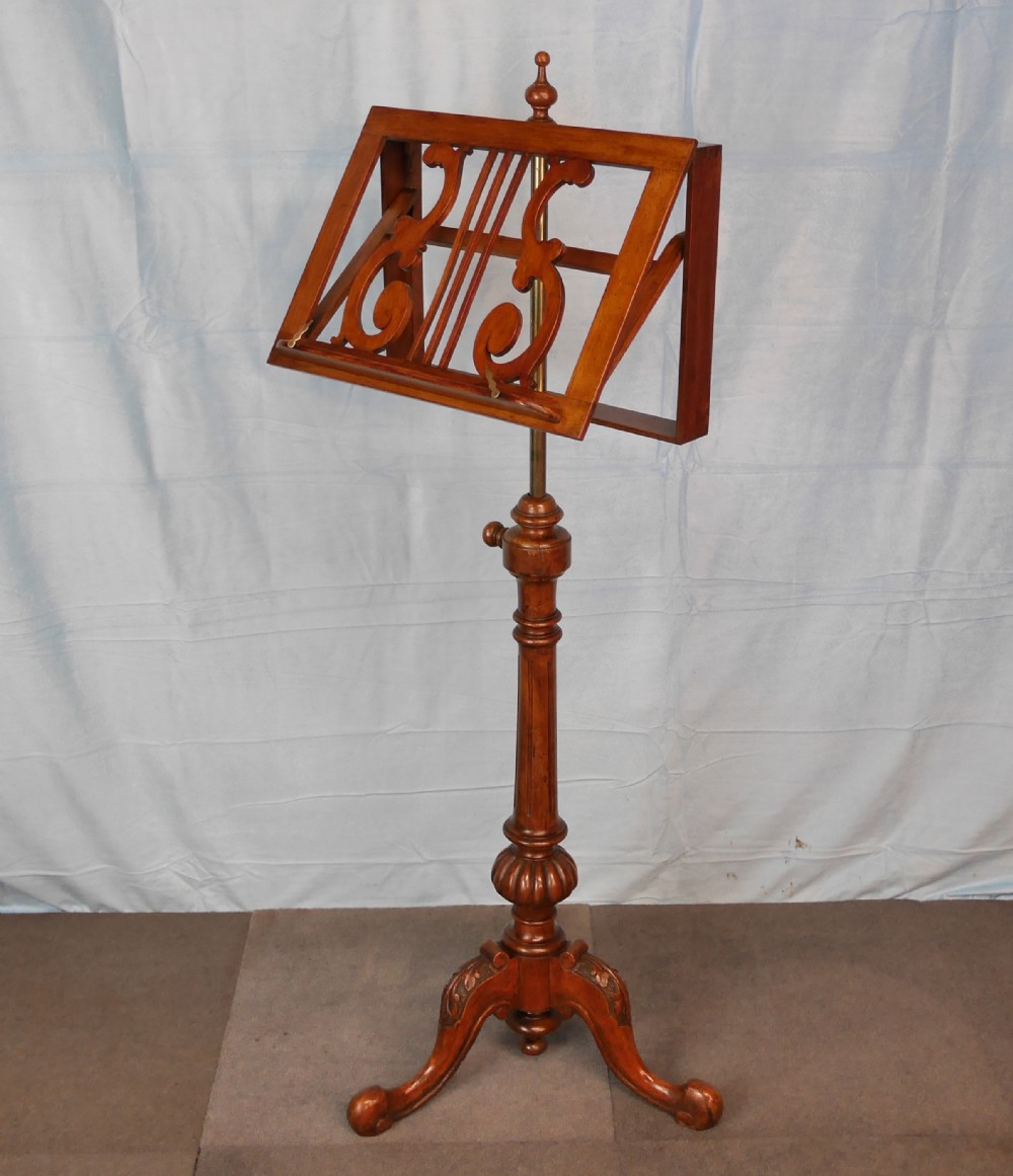 A Victorian mahogany adjustable music stand featuring an openwork lyre-patterned book rest, turned central column, and a tripod base.