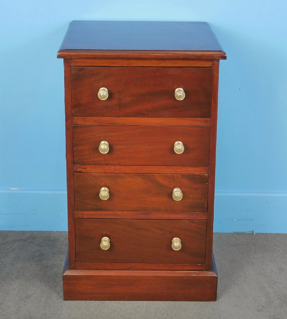 A small mahogany chest of drawers featuring four stacked drawers fitted with turned brass knobs, set on a straight plinth base.