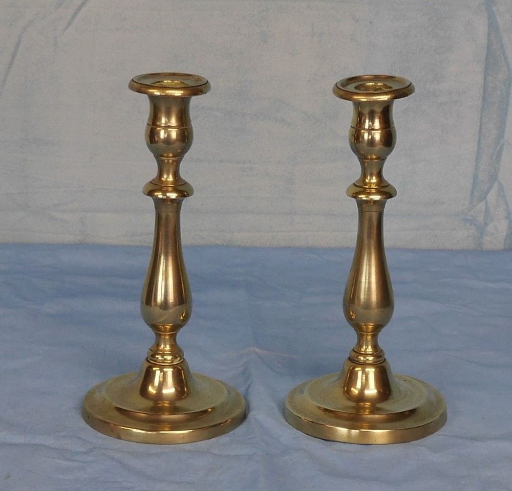 A pair of turned 19th-century brass candlesticks with baluster stems and circular stepped bases.