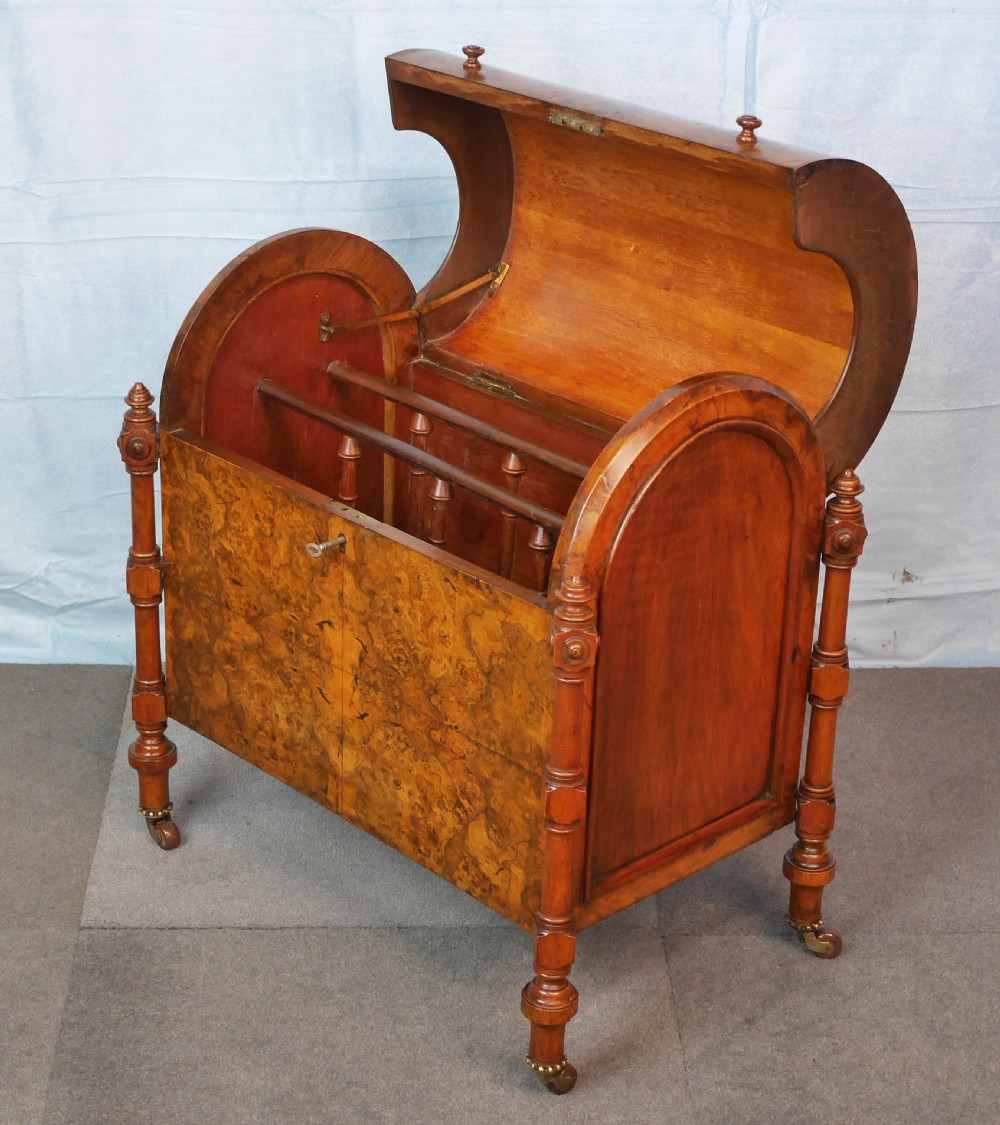 A Victorian burr walnut music canterbury featuring a rounded barrel lid, book-matched veneer panels, turned corner columns, and brass castors. View VI