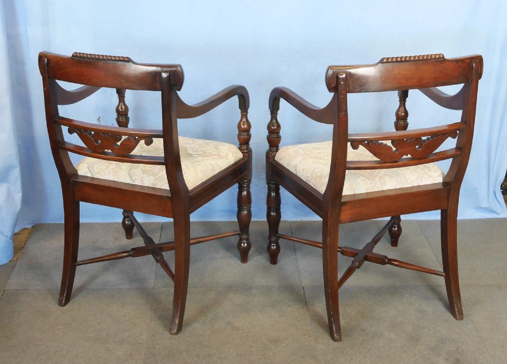 A pair of mahogany Regency style dining armchairs featuring carved backrests, sweeping armrests, turned front legs, and pattern upholstered seats. View VI