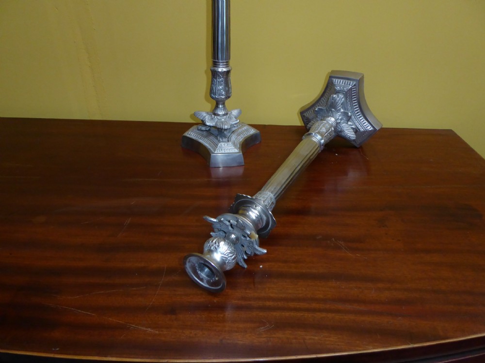 A pair of tall 19th-century silvered metal candlesticks featuring fluted central columns and ornate leaf-embellished tri-form bases. View III