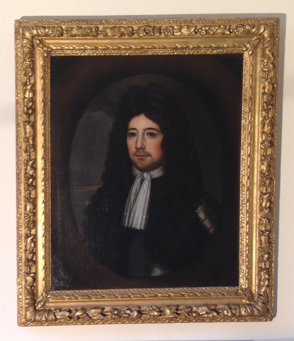 A seventeenth-century oil painting depicting a gentleman with a long dark wig and white cravat set inside a carved gold-leaf frame.