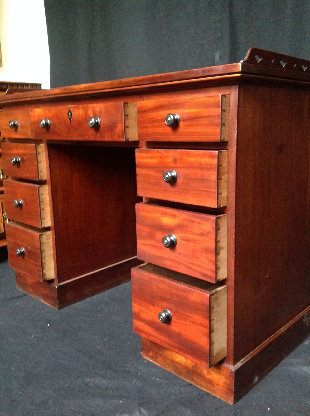 An early 19th-century mahogany pedestal desk featuring nine drawers with turned knobs, a central kneehole, and a pierced gallery back. View VII
