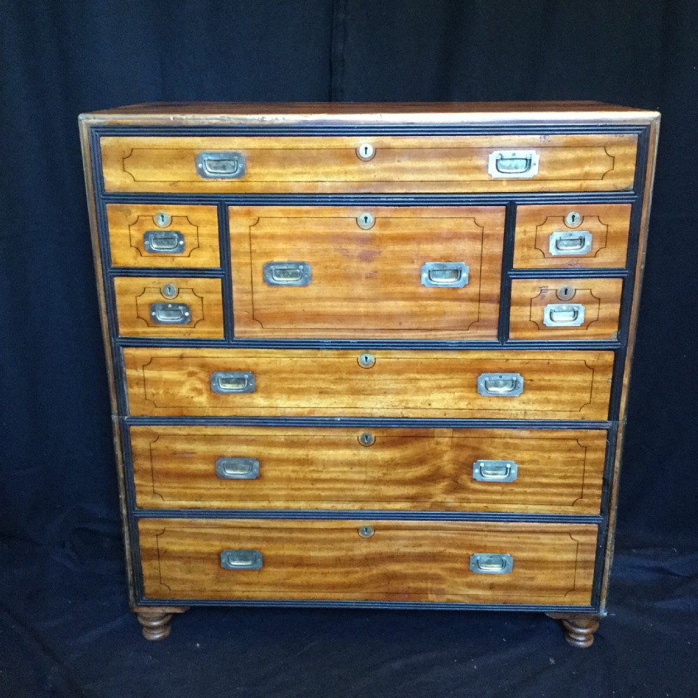 A rectangular mahogany campaign secretaire chest featuring multiple drawers, a fall-front writing compartment, and recessed brass pull handles.