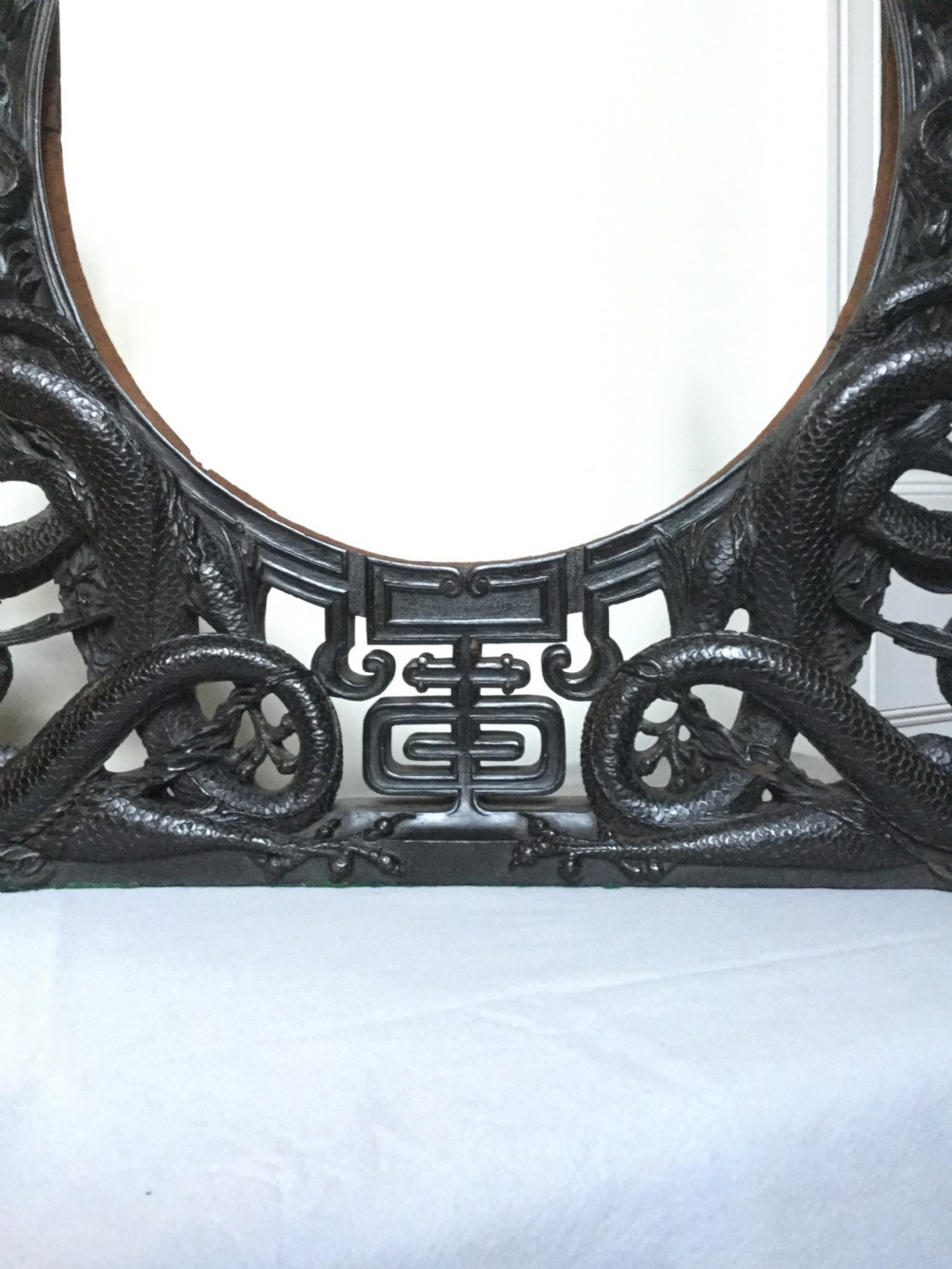 A circular brass plate set within an intricately carved dark wood frame featuring twin dragon motifs on a flat base. View IX