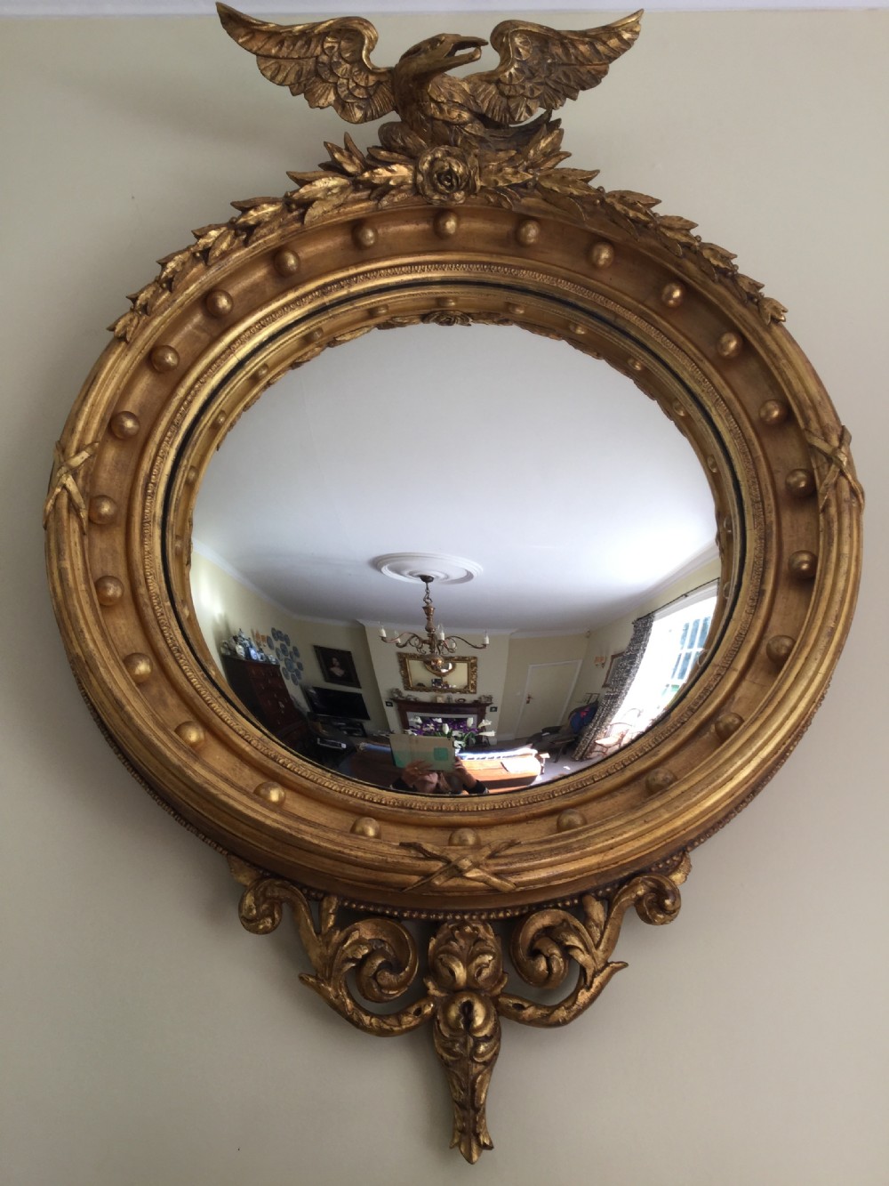 A circular gilded convex wall mirror topped with a carved eagle cresting and decorated with perimeter spherules. View III