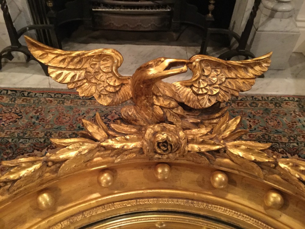 A circular gilded convex wall mirror topped with a carved eagle cresting and decorated with perimeter spherules. View XIII