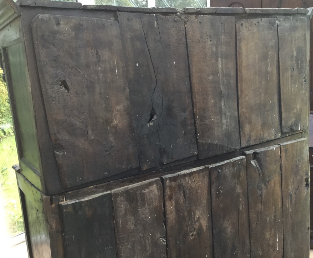 A dark oak 17th-century court cupboard with geometric fielded panelling, carved frieze, pendant drops, two drawers, and double lower doors. View VII