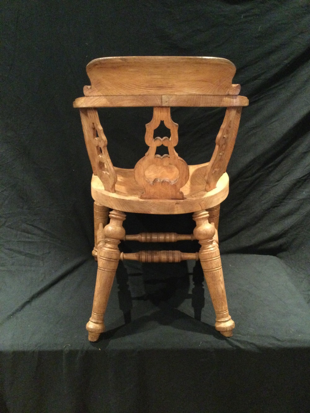 Set of four Victorian light brown wooden captains armchairs with curved backrests, pierced splats, shaped saddle seats, and turned legs. View X