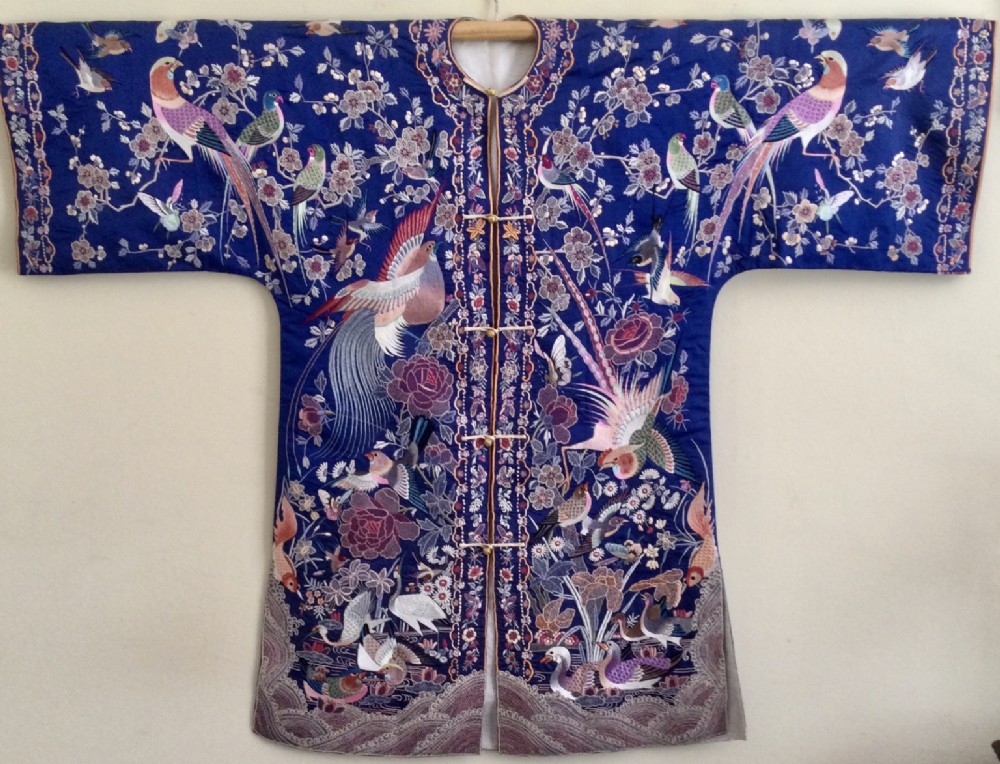 A cobalt blue silk garment featuring extensive hand embroidery of pheasants, birds, flowers, and frog button closures.