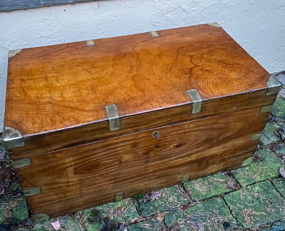 A rectangular warm brown camphor wood trunk featuring brass corner bindings, side carrying handles, and a central keyhole. View III