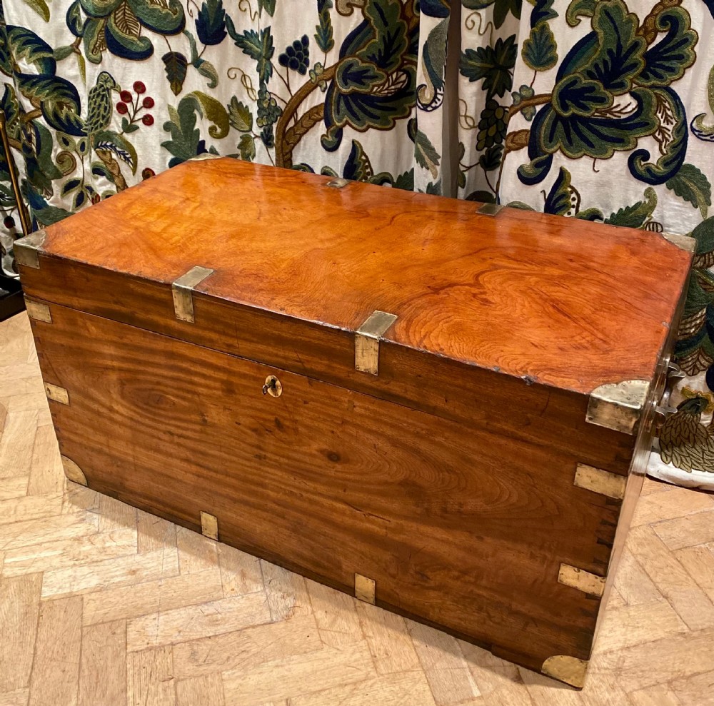 A rectangular warm brown camphor wood trunk featuring brass corner bindings, side carrying handles, and a central keyhole. View VII