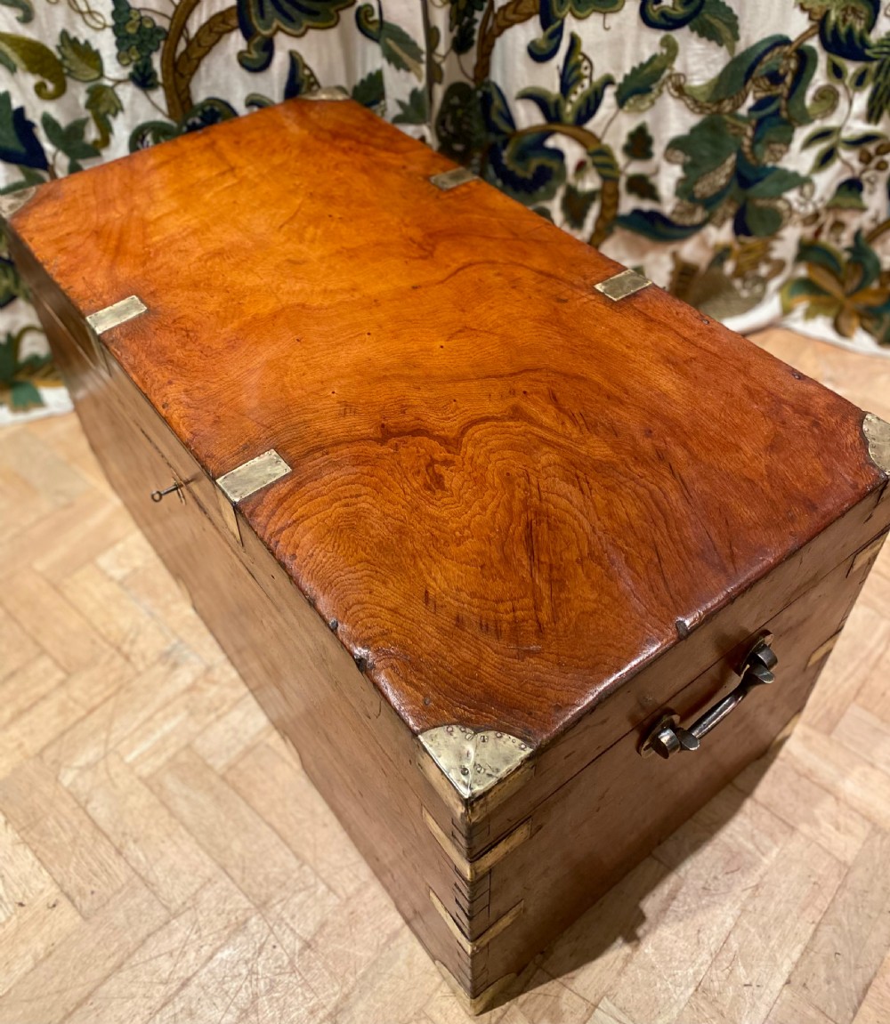 A rectangular warm brown camphor wood trunk featuring brass corner bindings, side carrying handles, and a central keyhole. View XI