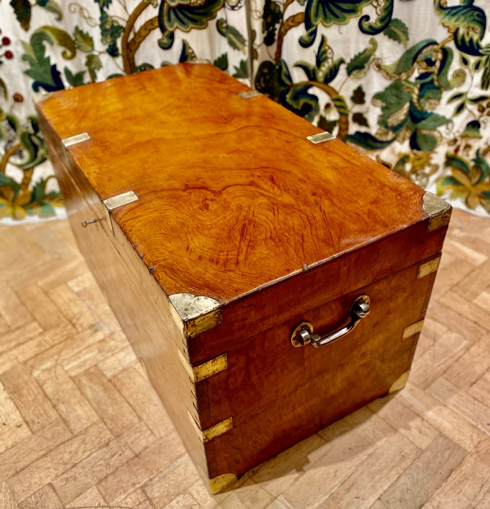 A rectangular warm brown camphor wood trunk featuring brass corner bindings, side carrying handles, and a central keyhole. View XII