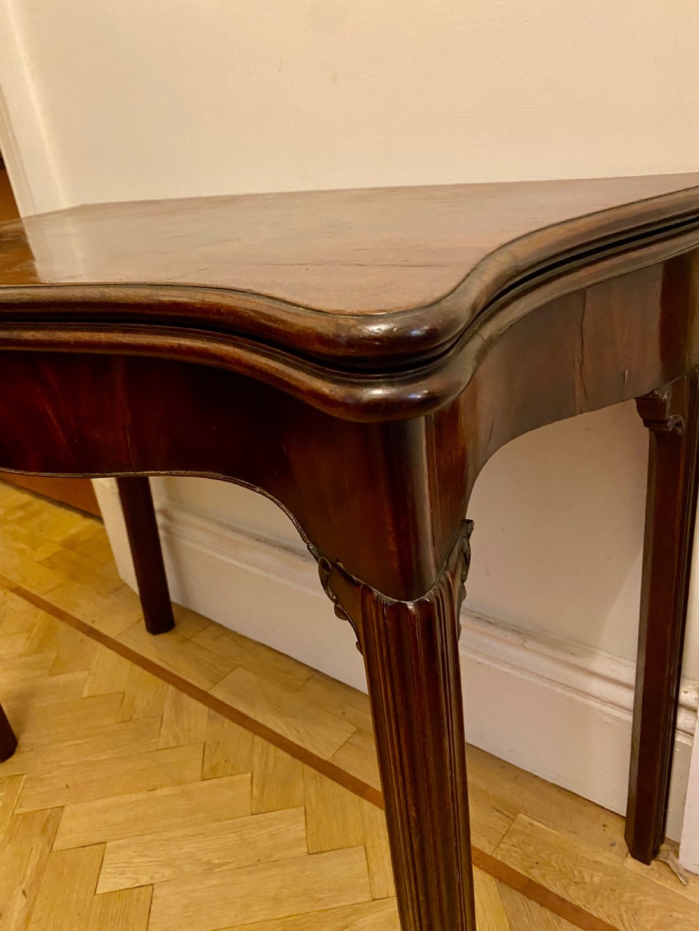 A Georgian mahogany fold-over card table featuring a serpentine front, flame mahogany top veneer, and moulded legs. View VII
