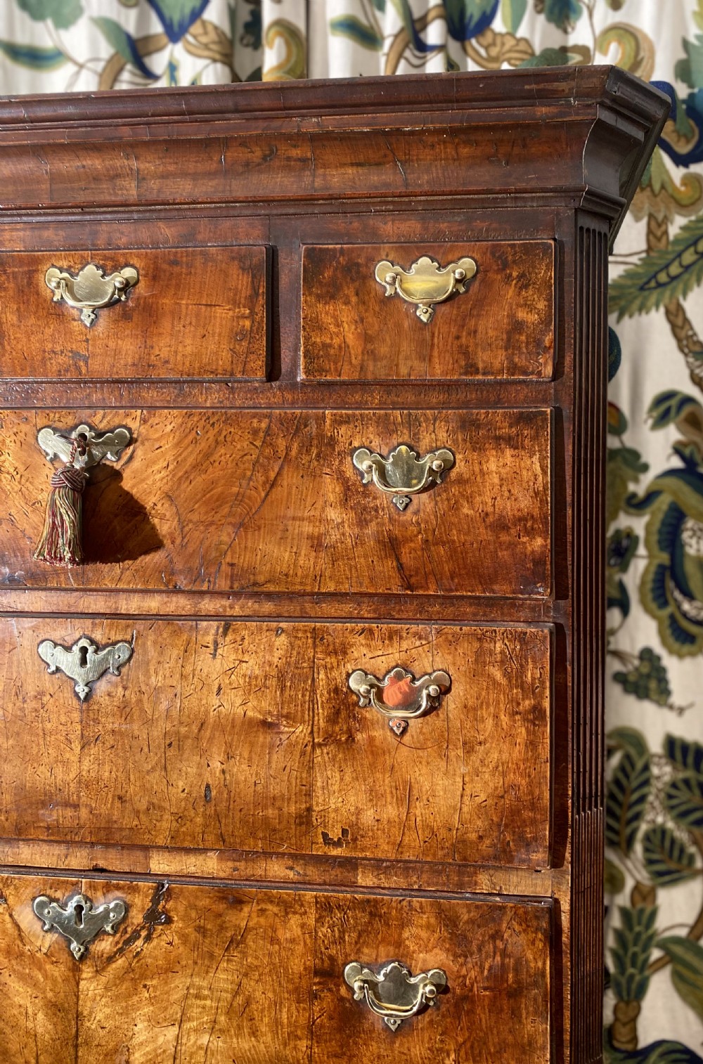 A tall Georgian burr walnut chest-on-chest featuring stacked drawers with brass drop handles and bracket feet. View III