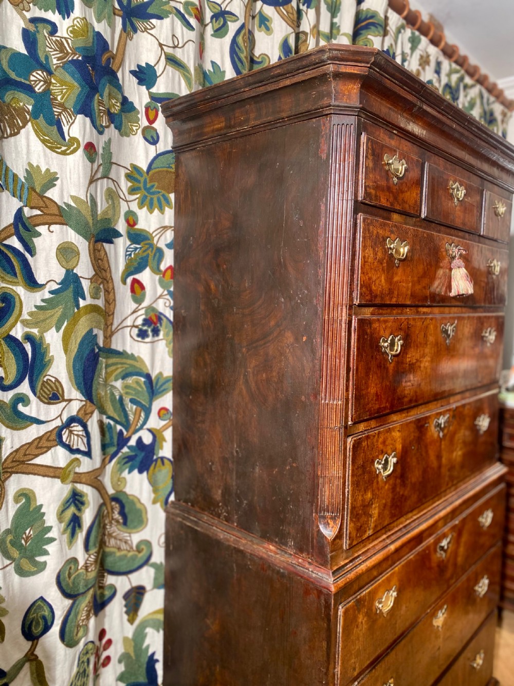 A tall Georgian burr walnut chest-on-chest featuring stacked drawers with brass drop handles and bracket feet. View V