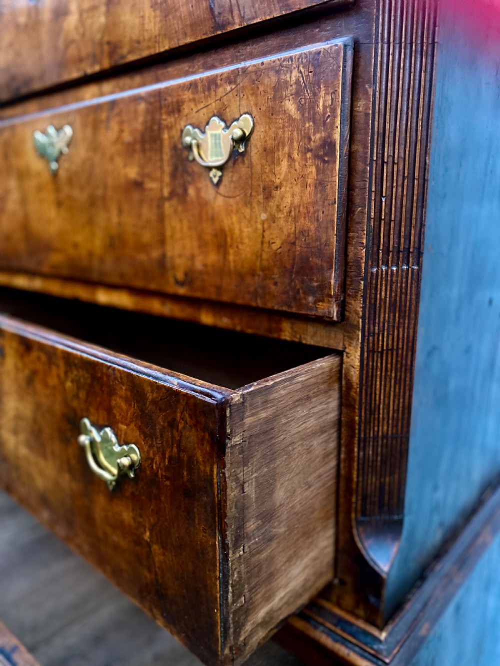 A tall Georgian burr walnut chest-on-chest featuring stacked drawers with brass drop handles and bracket feet. View X