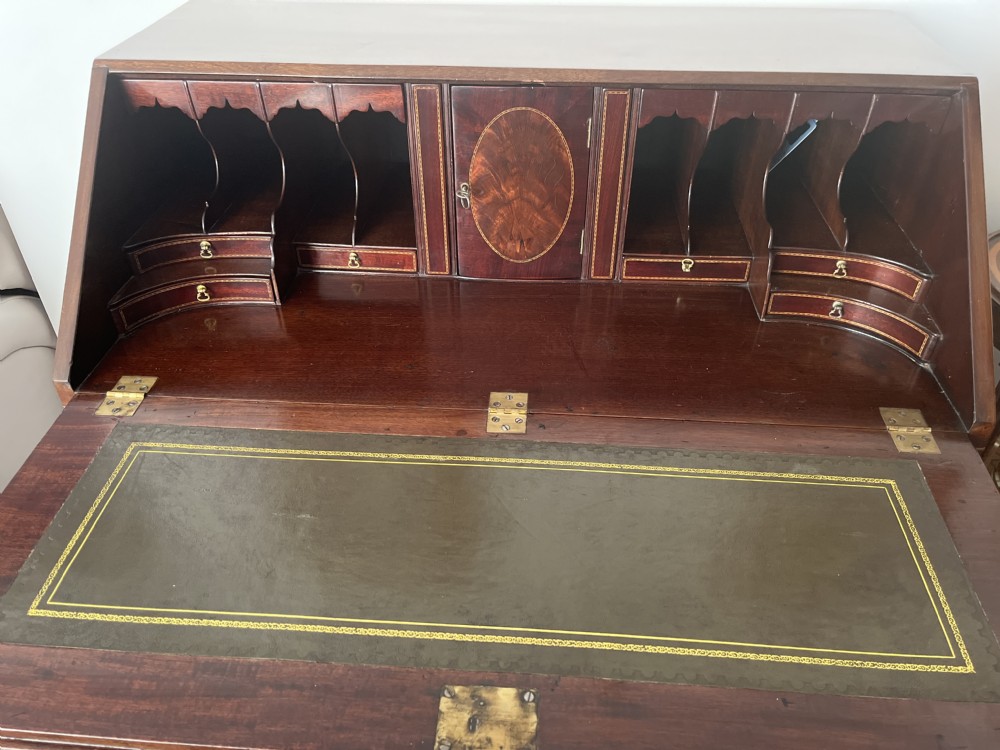 A Georgian mahogany writing bureau featuring a sloped hinged lid above four graduating drawers with brass swan-neck handles. View III