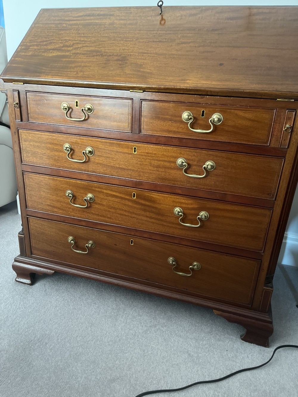 A Georgian mahogany writing bureau featuring a sloped hinged lid above four graduating drawers with brass swan-neck handles. View VI