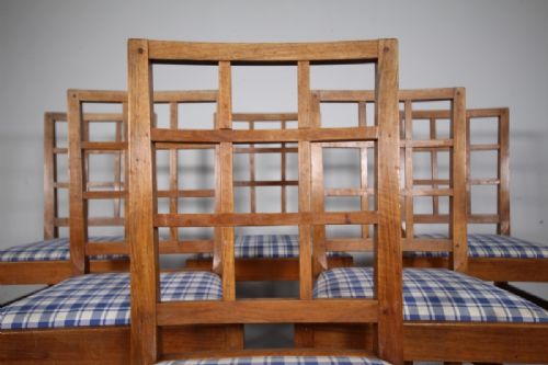 Set of six warm brown wooden dining chairs featuring open grid backrests and plaid upholstered drop-in seats. View VI