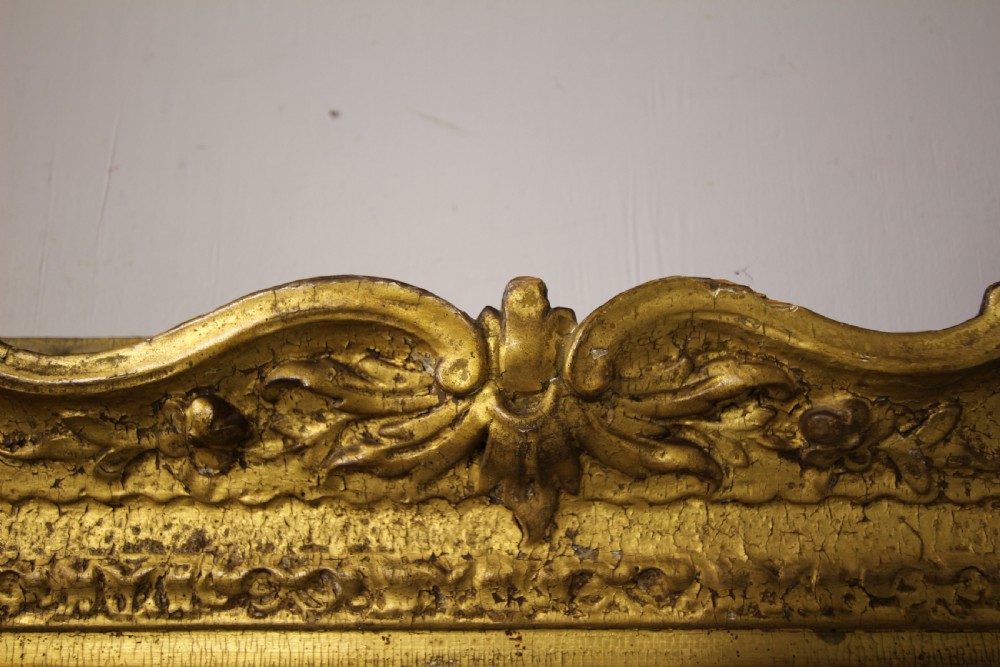 A rectangular Georgian wall mirror with an intricate hand-carved giltwood frame featuring foliage scrollwork and foxed mirror glass. View VII