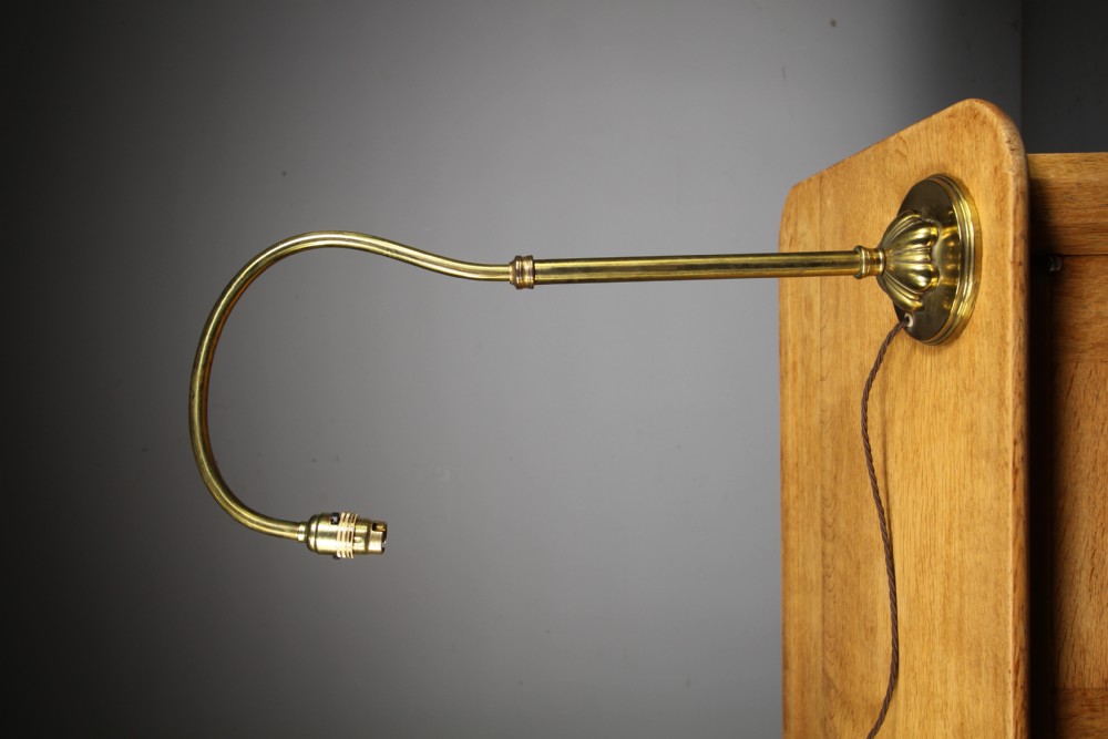 An antique brass Edwardian reading lamp featuring a sweeping curved swan-neck stem, fluted circular base, and braided brown flex cable. View V