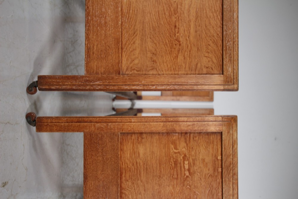 A pair of matching antique Arts and Crafts oak single bed frames with panelled headboards and footboards on castors. View VII