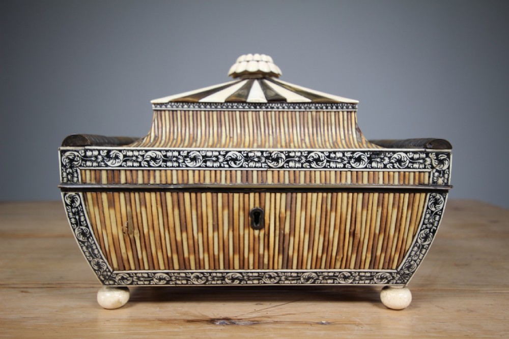 An antique sarcophagus-shaped porcupine quill box with engraved bone borders and bun feet.