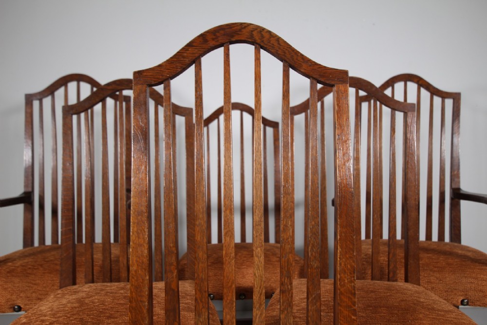 Set of six solid oak Arts and Crafts dining chairs featuring tall spindled backs and terracotta fabric upholstered seats. View III